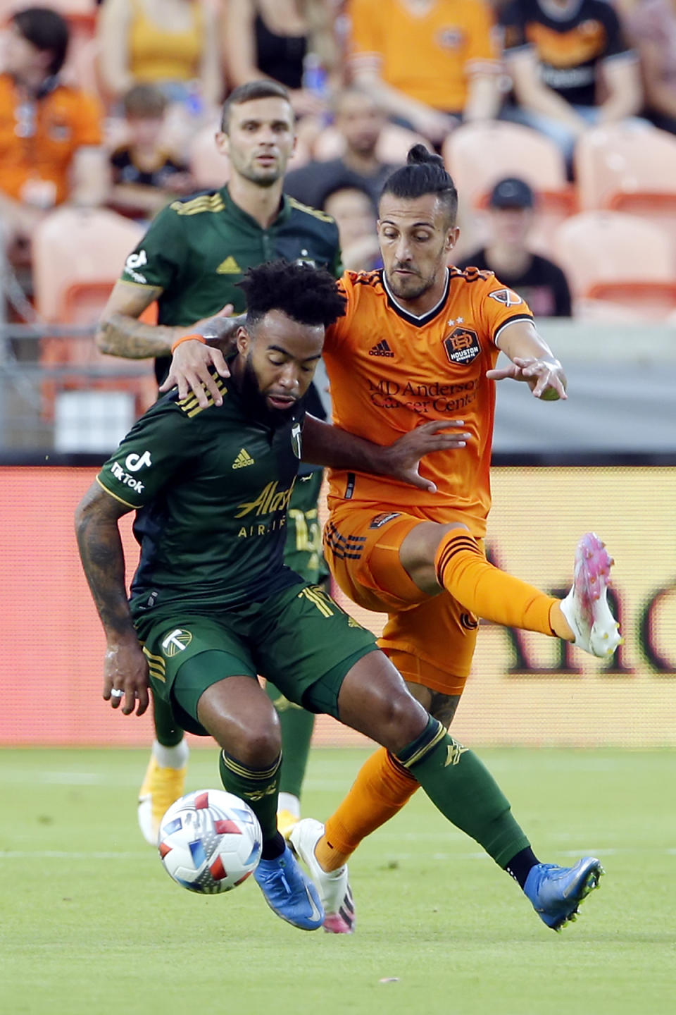 Portland Timbers midfielder Eryk Williamson, left, is pulled back by Houston Dynamo forward Maximiliano Urruti, right, as they chase the ball during the first half of an MLS soccer match Wednesday, June 23, 2021, in Houston. (AP Photo/Michael Wyke)
