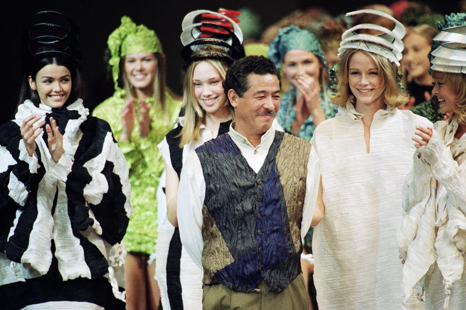 FILE - Japanese fashion designer Issey Miyake smiles standing among models after the presentation of his "1993/1994 fall/winter ready to wear collection" on March 17, 1993 in Paris, France. Miyake, who built one of Japan’s biggest fashion brands and was known for his boldly sculpted pleated pieces as well as former Apple CEO Steve Jobs’ black turtlenecks, has died. He was 84. He died Aug. 5, 2022, of liver cancer, Miyake Design Office said Tuesday, Aug. 9. (AP Photo/Lionel Cirroneau, File)