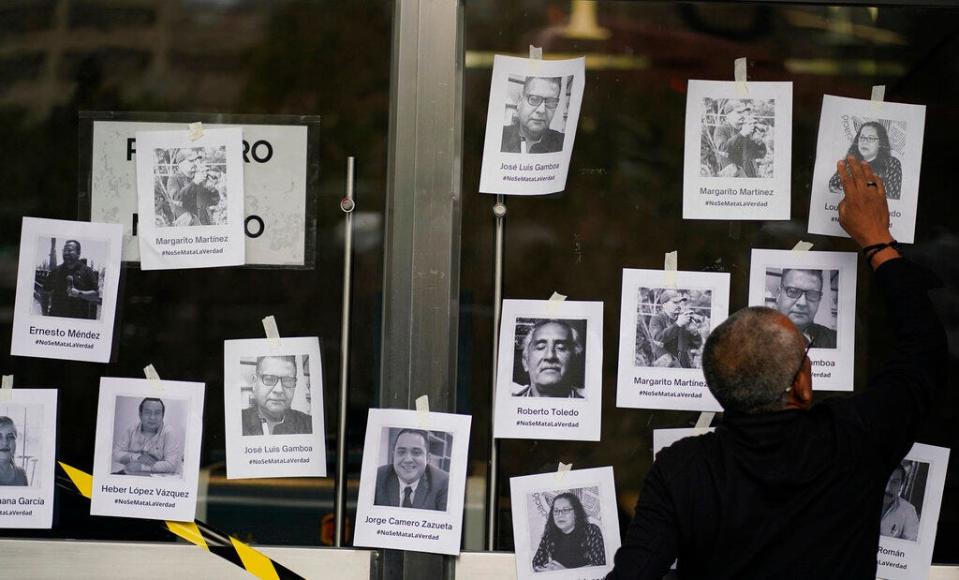 A man puts up photos of slain journalists after the murder of journalist Fredid Roman during a vigil to protest the crime, outside Mexico's Attorney General's office in Mexico City, Wednesday, Aug. 24, 2022. Roman was the 15th media worker killed so far this year in Mexico, where it is now considered the most dangerous country for reporters outside a war zone. (AP Photo/Eduardo Verdugo)