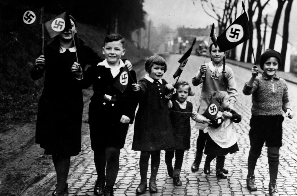 Ein Propagandafoto für die Presse: Kinder gehen mit Hakenkreuzfahnen in der Hand spazieren. 
 (Bild: rbb / Scherl / Süddeutsche Zeitung Photo)