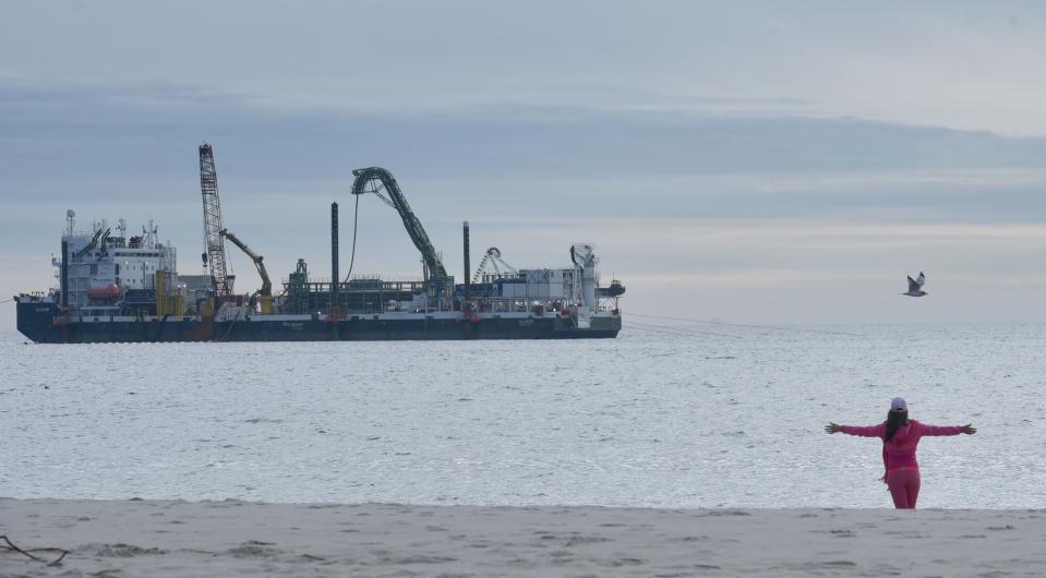 Edna Felix reaches out to the sky on Wednesday as she stretches before a jog at Craigville Beach in Centerville as the Vineyard Wind cable laying ship Ulisse works to bring the second of two offshore power cables ashore.