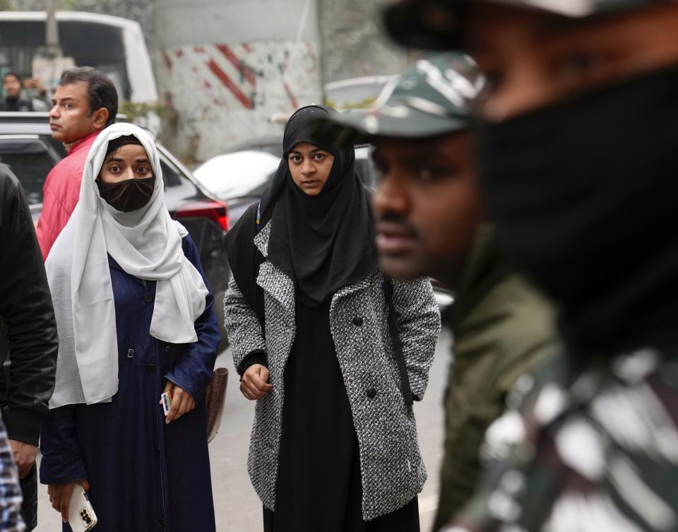 Students watch security personnel guard the main gate of Jamia Millia Islamia university in New Delhi, India, Wednesday, Jan. 25, 2023. Tensions escalated in the university after a student group said it planned to screen a banned documentary that examines Indian Prime Minister Narendra Modi's role during 2002 anti-Muslim riots, prompting dozens of police equipped with tear gas and riot gear to gather outside campus gates. (AP Photo/Manish Swarup)