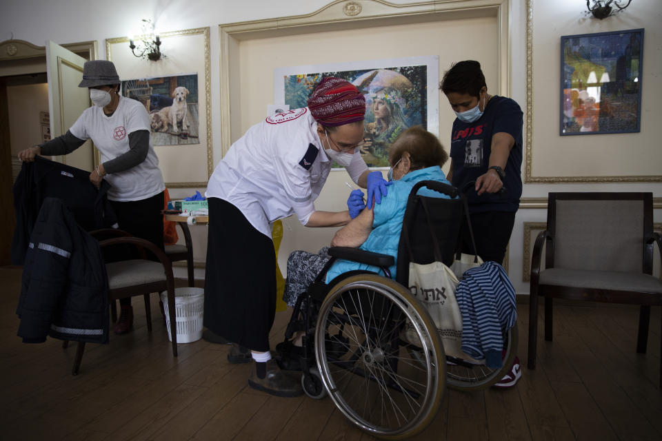 An Israeli woman receives the second Pfizer-BioNTech COVID-19 vaccine at a private nursing home, in Ramat Gan, Israel, Wednesday, Jan. 13, 2021. Israel has struck a deal with Pfizer, promising to share vast troves of medical data with the drugmaker in exchange for the continued flow of its COVID-19 vaccine. Critics say the deal is raising major ethical concerns, including possible privacy violations and a deepening of the global divide between wealthy countries and poorer populations, including Palestinians in the occupied West Bank and Gaza, who face long waits to be inoculated. (AP Photo/Oded Balilty)