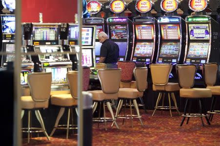 A person walks between unoccupied slot machines in the Condado Plaza Hotel after a spokesman announced that the casino is closing, in San Juan, Puerto Rico July 22, 2015. REUTERS/Alvin Baez