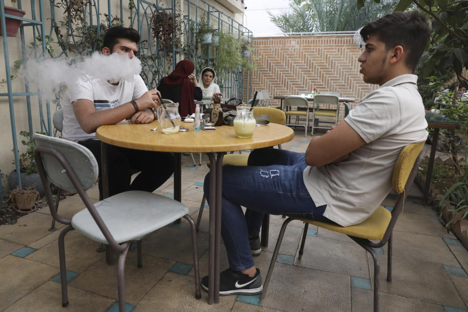 People spend their afternoon in a cafe in Tehran, Iran, Sunday, Sept. 20, 2020. Iran's president dismissed U.S. efforts to restore all U.N. sanctions on the country as mounting economic pressure from Washington pushed the local currency down to its lowest level ever on Sunday. (AP Photo/Vahid Salemi)