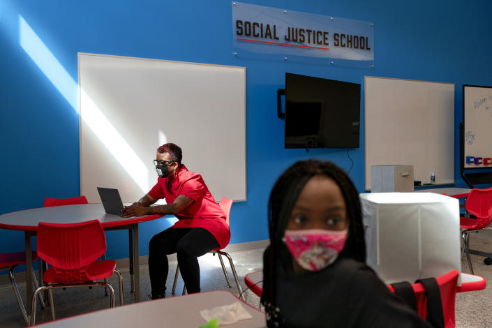 In this Tuesday, Sept. 29, 2020, photo a tech problem is solved by a teacher as a student attends her English Language Arts class at The Social Justice Public Charter School, in Washington. (AP Photo/Jacquelyn Martin)