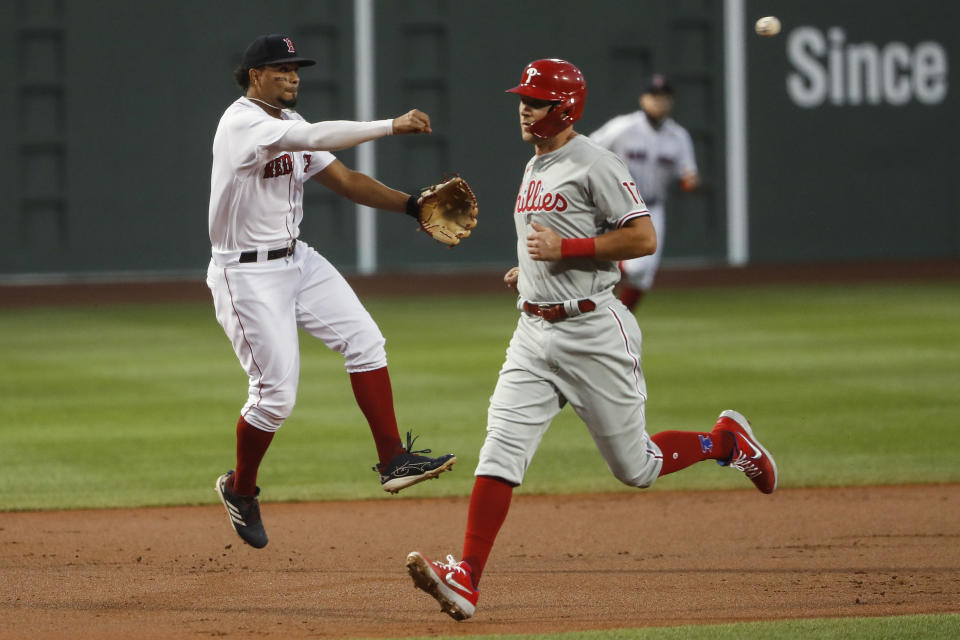 Boston Red Sox shortstop Xander Bogaerts throws past Philadelphia Phillies' Rhys Hoskins to get out J.T. Realmuto at first base during the first inning of a baseball game Tuesday, Aug. 18, 2020, at Fenway Park in Boston. (AP Photo/Winslow Townson)