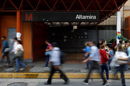 People walk past a closed metro station during a blackout in Caracas