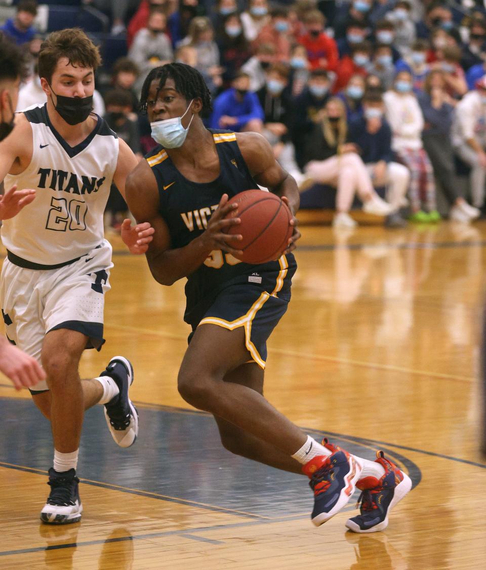 Victor forward Phil Nwugwo drives to the basket against Eli Adams (20). 