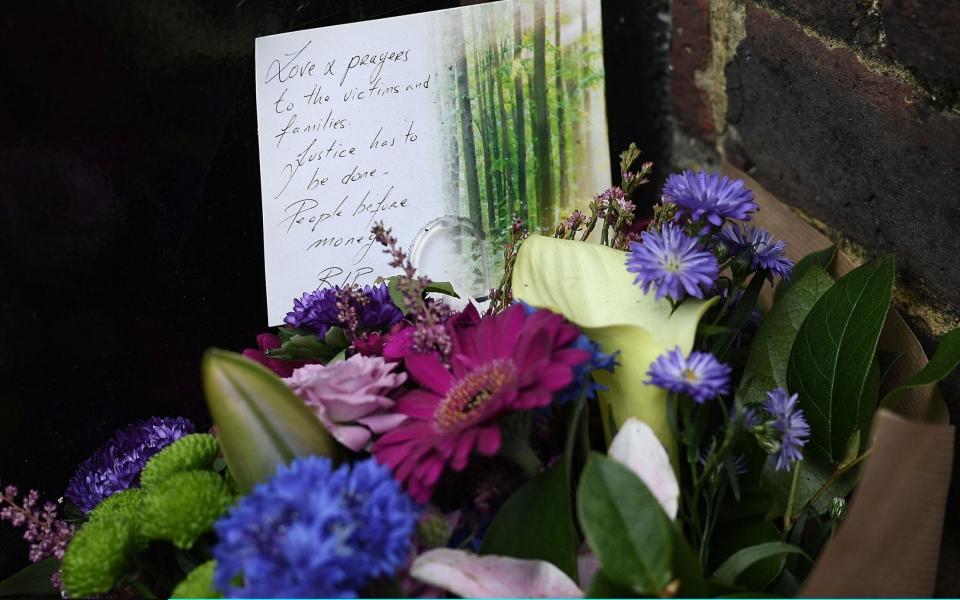 A bunch of flowers are left as a tribute near the burning  - Credit: Carl Court/Getty