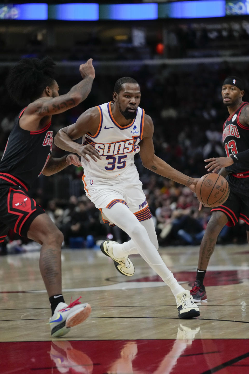Phoenix Suns forward Kevin Durant, right, dribbles around Chicago Bulls guard Coby White during the first half of an NBA basketball game, Wednesday, Nov. 8, 2023, in Chicago. (AP Photo/Erin Hooley)