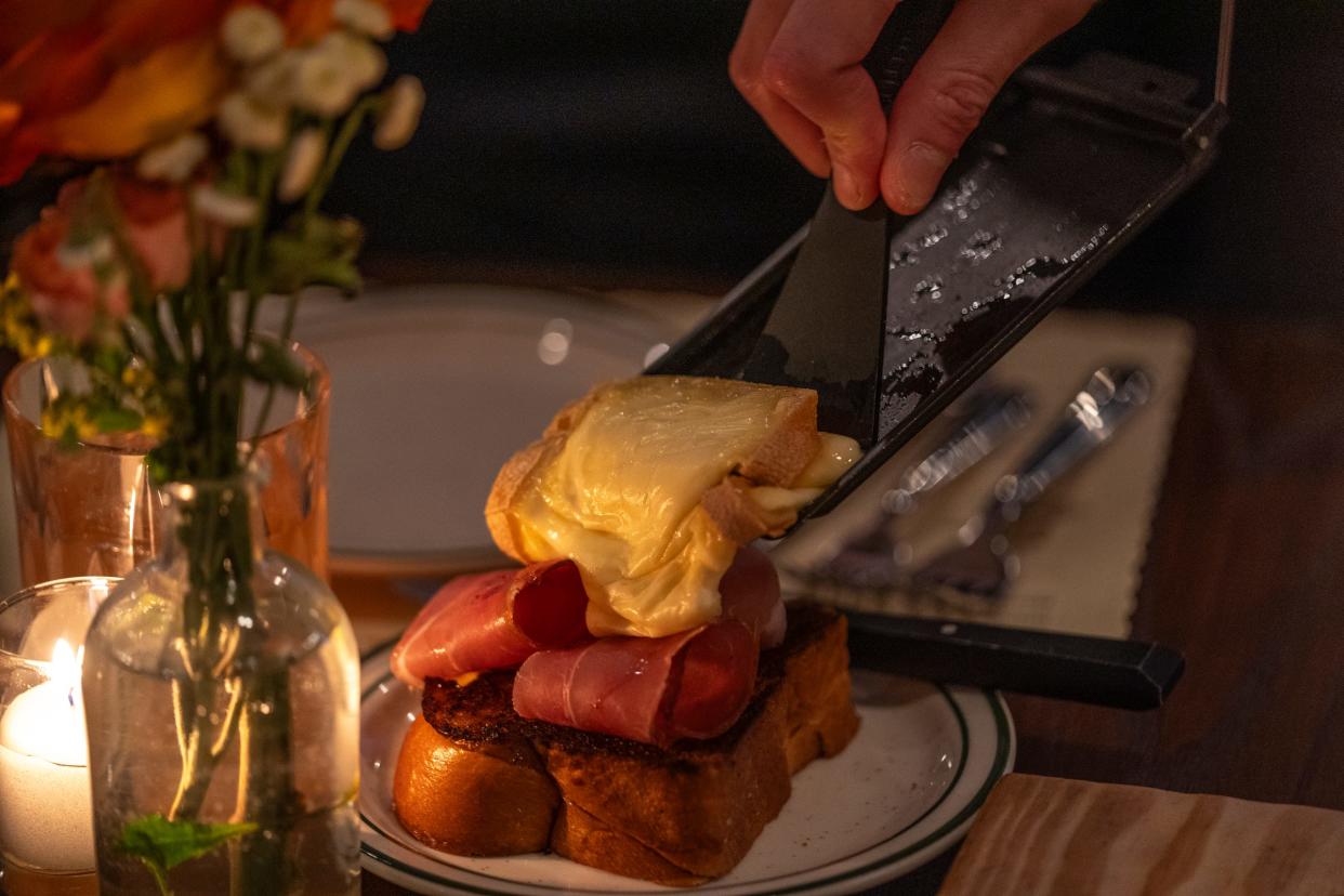 A server scrapes French Raclette onto brioche with speck and honey at Alpino in Detroit's Corktown neighborhood on Friday, February 16, 2024. The restaurant focuses on a cuisine inspired by the Alps and does so in a warm, elegant environment paired with excellent hospitality.