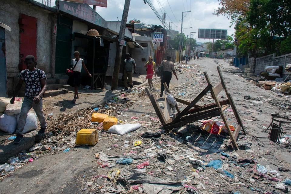 PHOTO: People walk past a barricade in a road in Port-au-Prince, Haiti, on March 20, 2024.  (Clarens Siffroy/AFP via Getty Images)