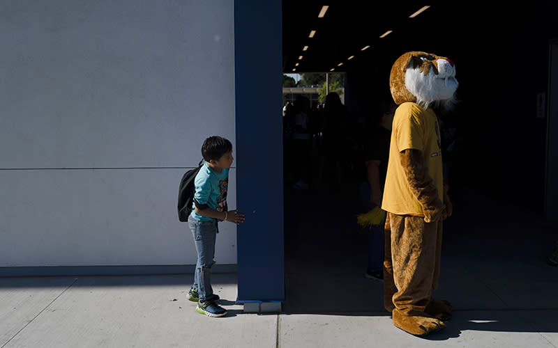 A second grader at Sunkist Elementary School stands behind a school mascot