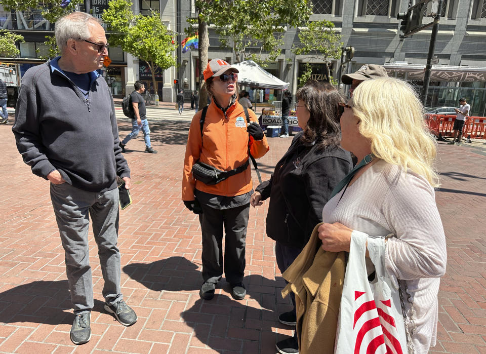 A welcome ambassador helps tourists find a cable car line on Market Street in San Francisco, Wednesday, June 21, 2023. San Francisco's downtown has seen an exodus of retailers and now a shopping mall owner is turning the complex over to its lender in the face of declining foot traffic and empty office space. While San Francisco faces some of its own unique issues, such as a heavy reliance on tech workers, most of them working largely remotely, the problems serve as warning signs for other downtowns across the country, which are also feeling some pain. (AP Photo/Eric Risberg)