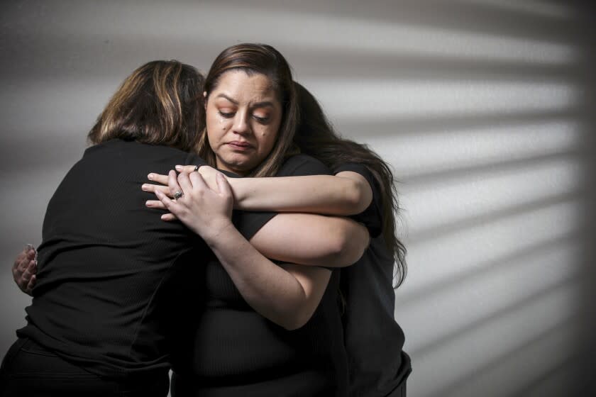 Menifee, CA - January 13: Stephanie Reyes, 37, center, who lost her husband to COVID in September 2020, is comforted by her two daughters Marissa Reyes, 18, left, and Reyna Reyes, 15, at their home on Thursday, Jan. 13, 2022 in Menifee, CA. (Irfan Khan / Los Angeles Times)