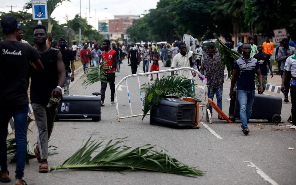 Protesters walk through a barricade along a road during a protest  - AKINTUNDE AKINLEYE/EPA-EFE/Shutterstock