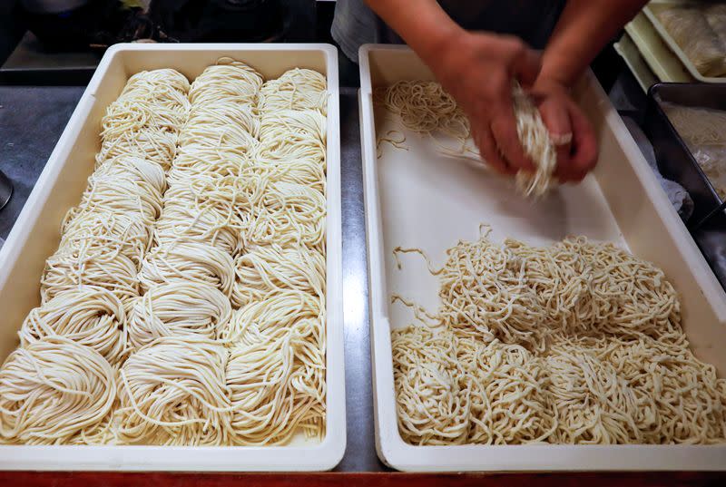 An employee of ramen noodle shop 'Shirohachi' prepares noodles inside the shop, managed by sixty-year-old Yashiro Haga, amid the coronavirus disease (COVID-19) outbreak, in Tokyo