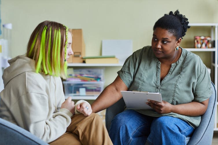 A counselor comforts a teenage student who has a sad expression.