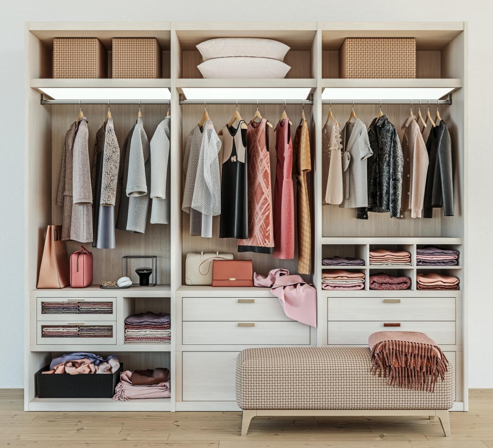 modern wooden wardrobe with women clothes hanging on rail in walk in closet design interior, 3d rendering