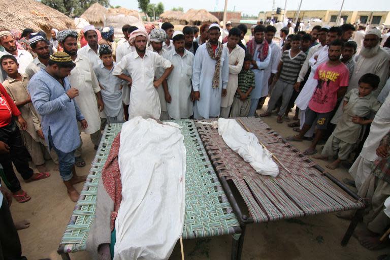 Indian villagers gather near the bodies of those killed in cross-border firing between Indian and Pakistani troops at Jeiora village in the RS Pura sector near Jammu on August 23, 2014