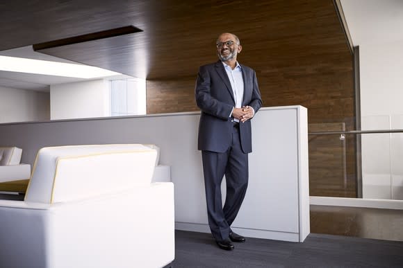 A smiling Adobe CEO Shantanu Narayen standing next to a white counter.