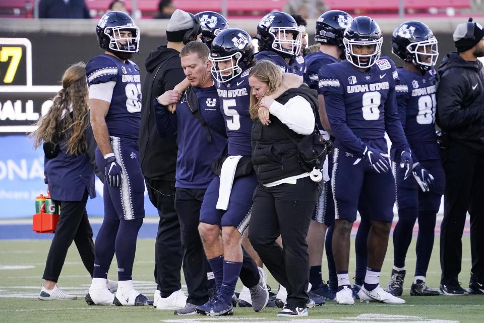 Utah State quarterback Cooper Legas (5) is helped off the field by team training staff during the second half of the First Responder Bowl NCAA college football game against Memphis, Tuesday, Dec. 27, 2022, in Dallas. (AP Photo/Sam Hodde)