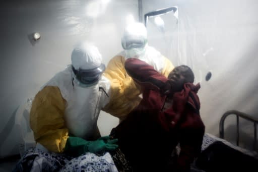 An Ebola patient is lifted up by two medical workers in the town of Beni, near the Ugandan border