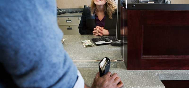 bank teller smiling at customer who has wallet in hand.jpg