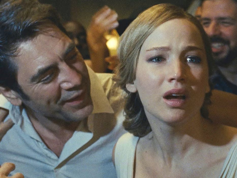 A scene from "Mother!" where Javier Bardem and Jennifer Lawrence are seated next to each other while Lawrence is exclaiming as if in fear.