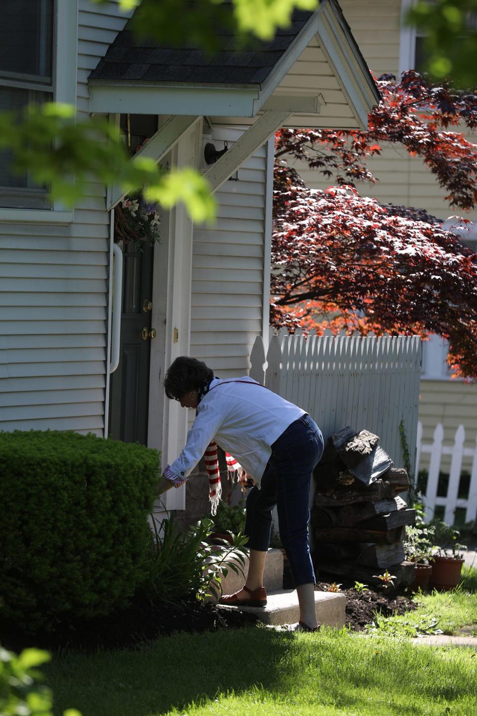 Peg Garlock puts flags in the planters outside her door before the start of Memorial Day parade in Pittsford. Garlock, who lives along the parade route on South Main Street, said she was raised to always be a participant in Memorial Day and had family members who served in the military going back to World War I.