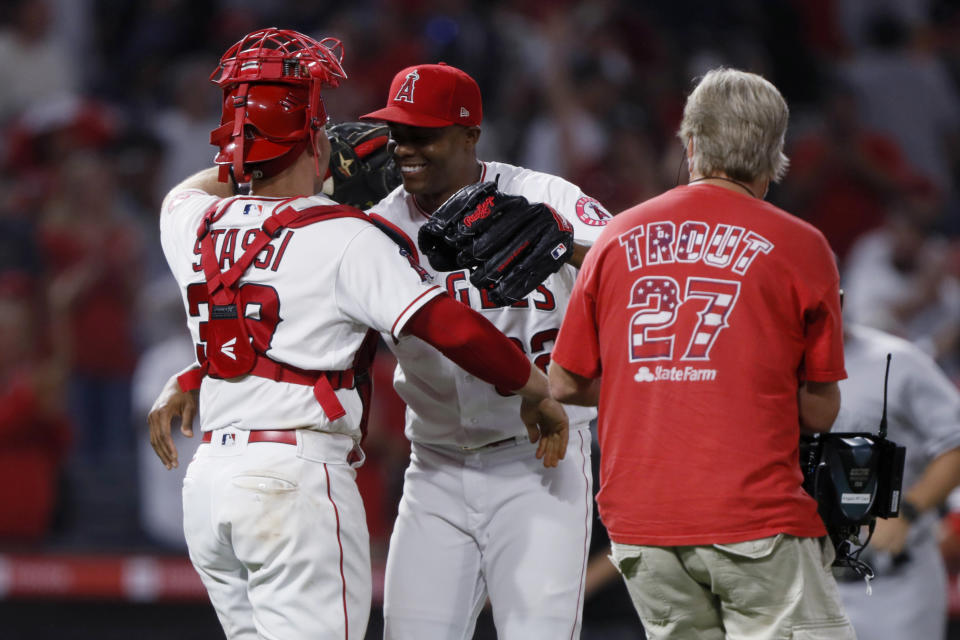 Los Angeles Angels relief pitcher Raisel Iglesias, center, hugs catcher Max Stassi after the Angels defeated the New York Yankees 6-4 in a baseball game in Anaheim, Calif., Tuesday, Aug. 31, 2021. (AP Photo/Alex Gallardo)