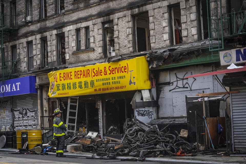 A firefighter looks through debris in the aftermath of a fire which authorities say started at an e-bike shop and spread to upper-floor apartments, Tuesday June 20, 2023, in New York. (AP Photo/Bebeto Matthews)