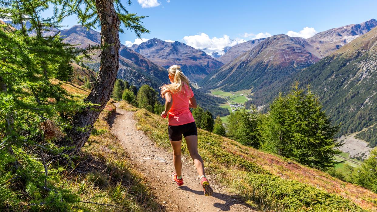  Action photo of athlete woman trail runner, running on a mountain path 