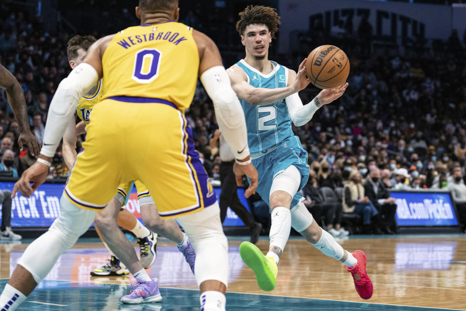 Charlotte Hornets guard LaMelo Ball (2) passes the ball while guarded by Los Angeles Lakers guard Russell Westbrook (0) during the first half of an NBA basketball game in Charlotte, N.C., Friday, Jan. 28, 2022. (AP Photo/Jacob Kupferman)