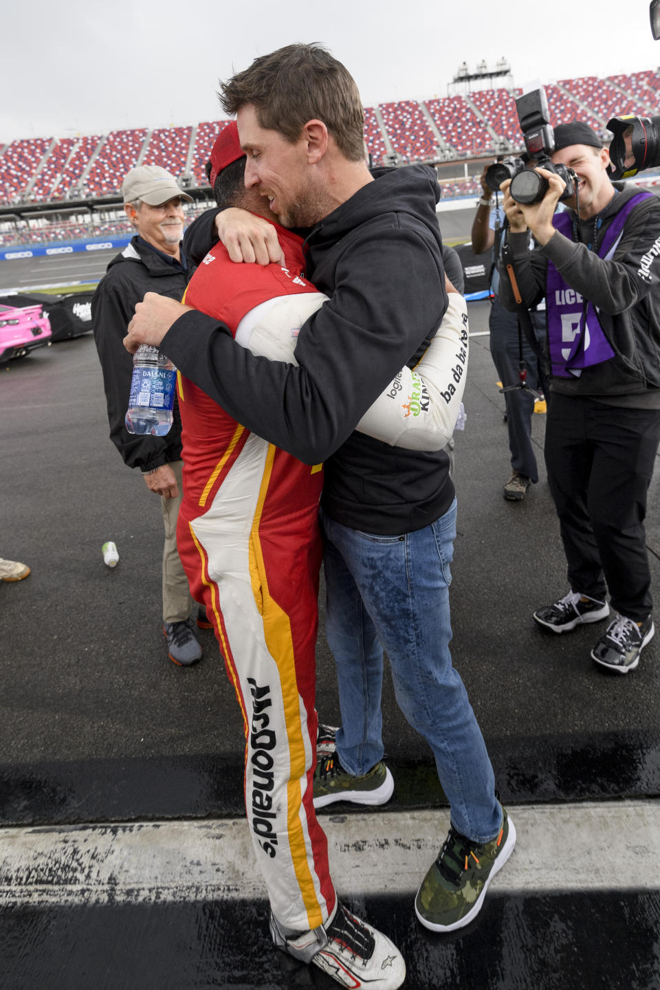 Bubba Wallace, front left, is congratulated by Denny Hamlin, front right, after Wallace was pronounced the winner while on pit row during a rain delay in a NASCAR Cup series auto race Monday, Oct. 4, 2021, in Talladega, Ala. (AP Photo/John Amis)