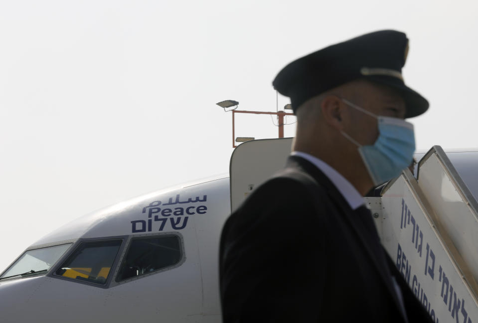 A flight crew member stands in front of the Israeli flag carrier El Al's airliner bearing the Arabic, English and Hebrew word for "peace" and which will carry Israeli and U.S. delegations to Abu Dhabi for talks meant to put final touches on the normalization deal between the United Arab Emirates and Israel, at Ben Gurion International Airport, near Tel Aviv, Israel Monday, Aug. 31, 2020. (Nir Elias/Pool Photo via AP)