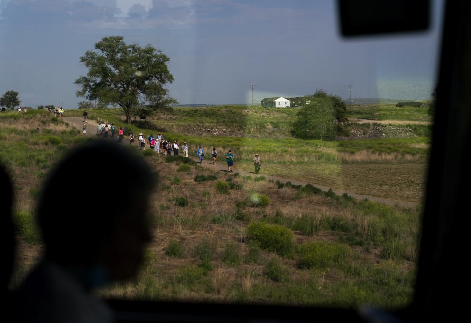 A Minidoka Pilgrimage tour for elders with limited mobility passes by another tour walking the ground of the Minidoka National Historic Site, Saturday, July 8, 2023, in Jerome, Idaho. (AP Photo/Lindsey Wasson)