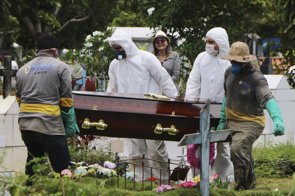 A relative stands at a distance during the burial of Robson de Souza Lopes at Parque Taruma cemetery in Manaus, Brazil, Tuesday, March 31, 2020. According to authorities at the Amazonas Health Secretary, the 43-year-old musician died Monday after being diagnosed with COVID-19. (AP Photo/Edmar Barros)