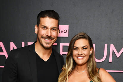 Jax and Brittany smiling together in front of a black and pink step and repeat.