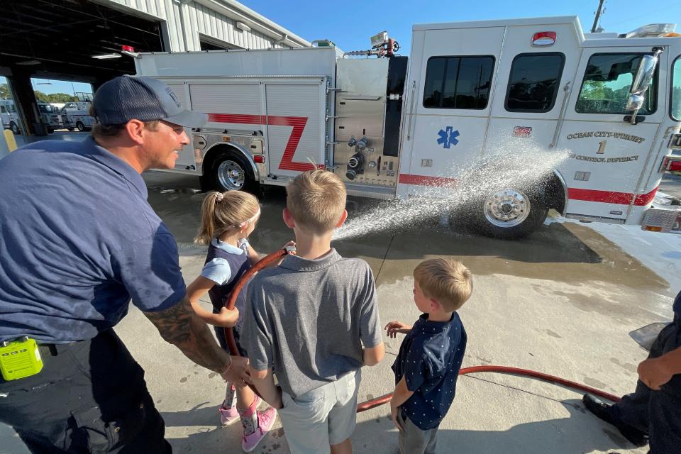 Ocean City-Wright Fire Control District firefighter Jesse Kapustik helps Rebekah Mixon hose down the department's new firetruck during a ceremony Tuesday evening at the station on Racetrack Road.
