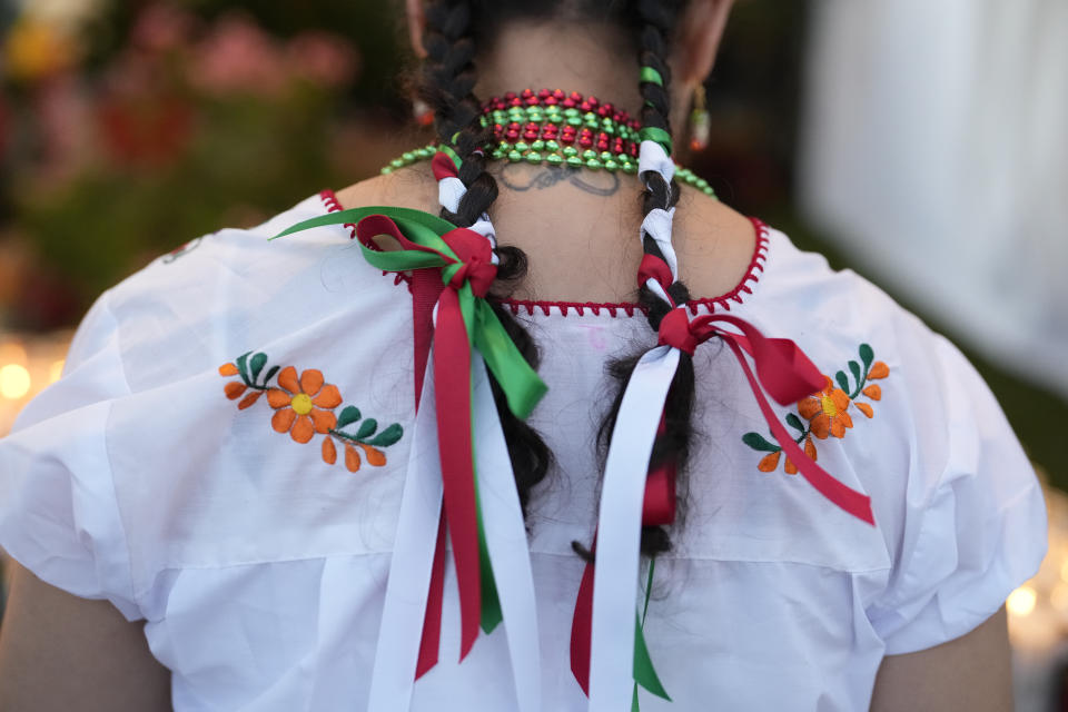 A woman wears a traditional embroidered top and ribbons in the colors of the Mexican flag, during a festival honoring the Virgin of Guadalupe, one of several apparitions of the Virgin Mary witnessed by an indigenous Mexican man named Juan Diego in 1531, at St. Ann Mission in Naranja, Fla., Sunday, Dec. 10, 2023. For this mission church where Miami's urban sprawl fades into farmland and the Everglades swampy wilderness, it's the most important event of the year, both culturally and to fundraise to continue to minister to the migrant farmworkers it was founded to serve in 1961. (AP Photo/Rebecca Blackwell)
