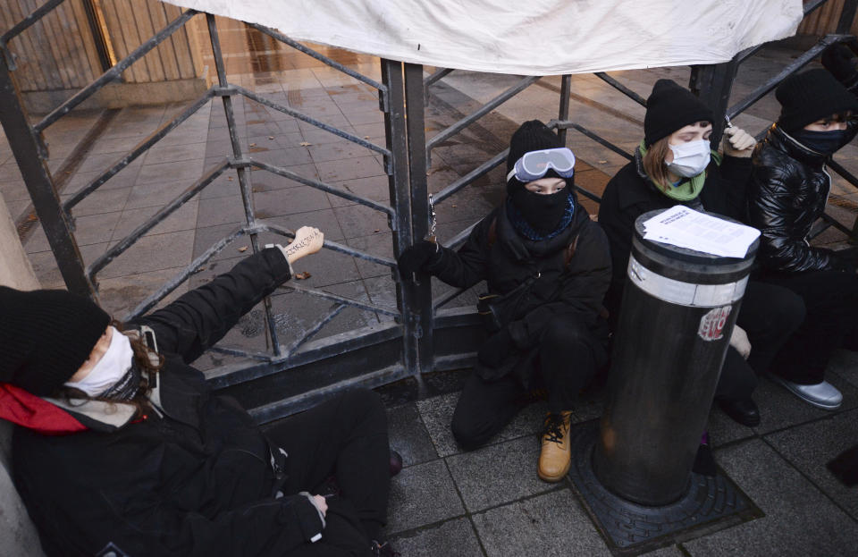 A woman is handcuffed to the gate in front of the Education Ministry building in Warsaw, Poland, on Monday Nov. 23, 2020. Police detained several people as women-led protests over abortion rights flared up again in Warsaw and elsewhere in Poland. The protests, organized by the group Women's Strike, have been occurring regularly ever since the country's constitutional court issued an Oct. 22 ruling that further tightens an abortion law that was already one of the most restrictive in Poland.(AP Photo/Czarek Sokolowski)