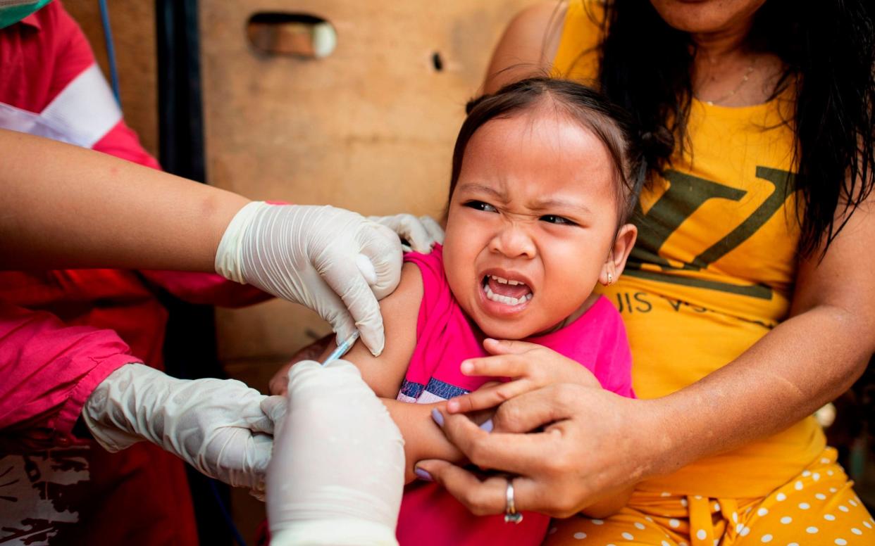 A child receives a vaccine during a measles immunisation drive in the Philippines - AFP