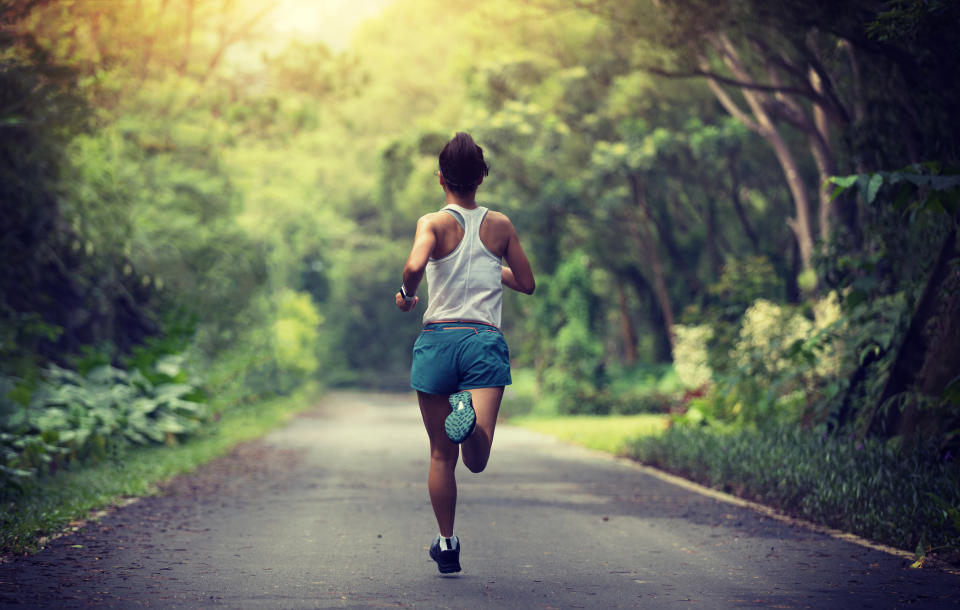 Female runner running at summer park trail . Healthy fitness woman jogging outdoors.