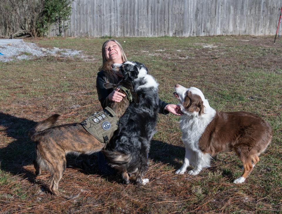 Pensacola Humane Society interim executive director Manda Moore-Joseph is surrounded by her dogs Isa, from left, Gunner, and Axl at their Holley By The Sea home on Friday, Dec. 16, 2022.