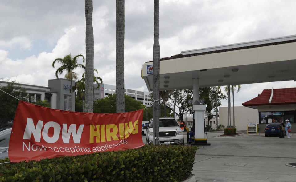 In this, Wednesday, May 6, 2020 photo, a now hiring sign is displayed on a street corner in North Miami Beach, Fla. Initial jobless claims in Florida dropped by more than half last week compared to the prior week, according to figures released Thursday, as unemployed Floridians continued facing problems signing up and receiving benefits because of difficulties with a computer system. (AP Photo/Wilfredo Lee)