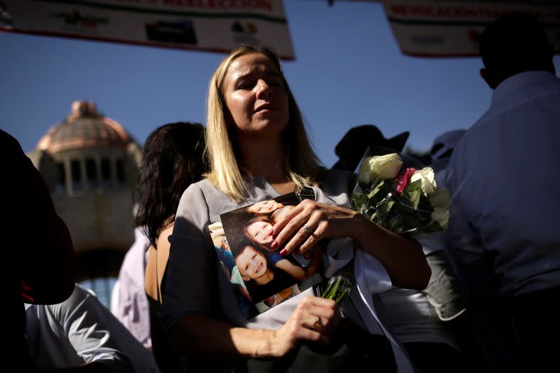 Adriana LeBaron a member of the LeBaron family, who saw nine of its members murdered in November, holds pictures during a march to protest against violence on the first anniversary of President Andres Manuel Lopez Obrador taking office, in Mexico City