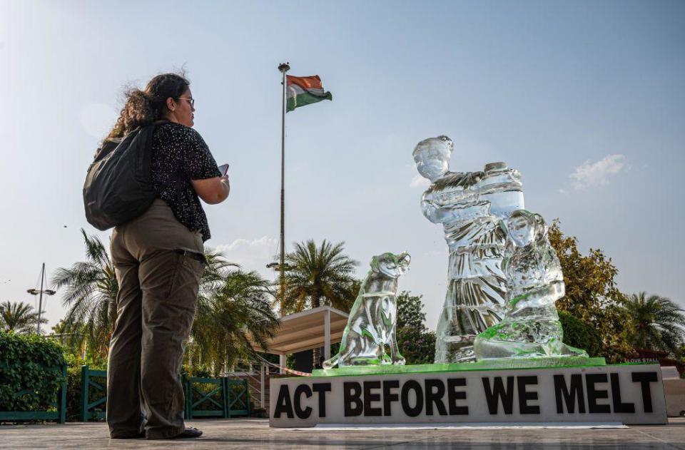 A visitor takes a photo of the ice sculpture, melting under the heatwave in Delhi to show the impact of heatwaves across the country, as part of a protest staged by a Greenpeace activist at a mall in Delhi. The 8 foot tall sculpture shows a woman with a child and a dog - some of the most vulnerable communities affected by heatwaves and other extreme weather events