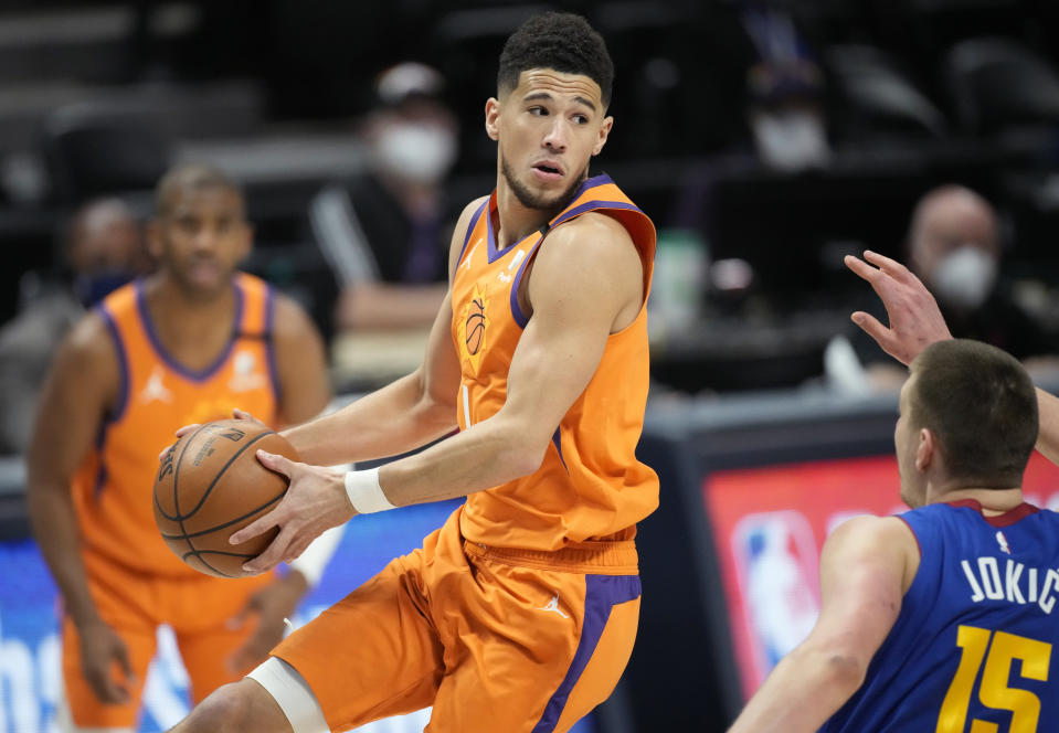 Phoenix Suns guard Devin Booker, front left, looks to pass the ball as Denver Nuggets center Nikola Jokic, right, defends in the first half of Game 3 of an NBA second-round playoff series Friday, June 11, 2021, in Denver. (AP Photo/David Zalubowski)